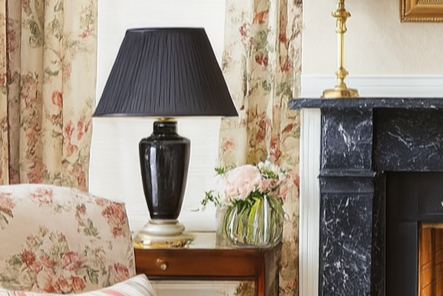 Living room with floral armchair, black lamp, and marble fireplace.